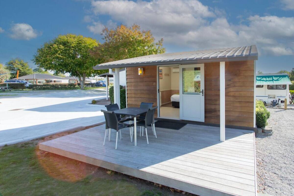 Een knus, modern vakantiehuisje met een houten terras en een eethoek.