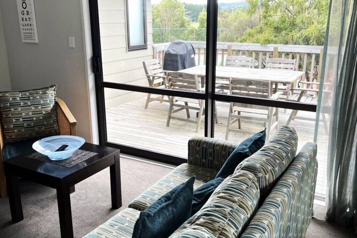 Een woonkamer met een bank, een tafel en uitzicht op een terras.
