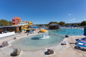 A water park with a large pool, water slides, and lounge areas.