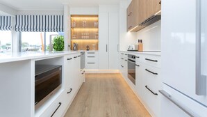 Une cuisine moderne avec des meubles blancs, un four encastré et un plan de travail en bois.