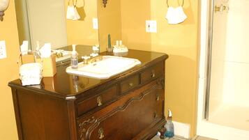 A bathroom with a wooden vanity, a mirror, a sink, and a shower.