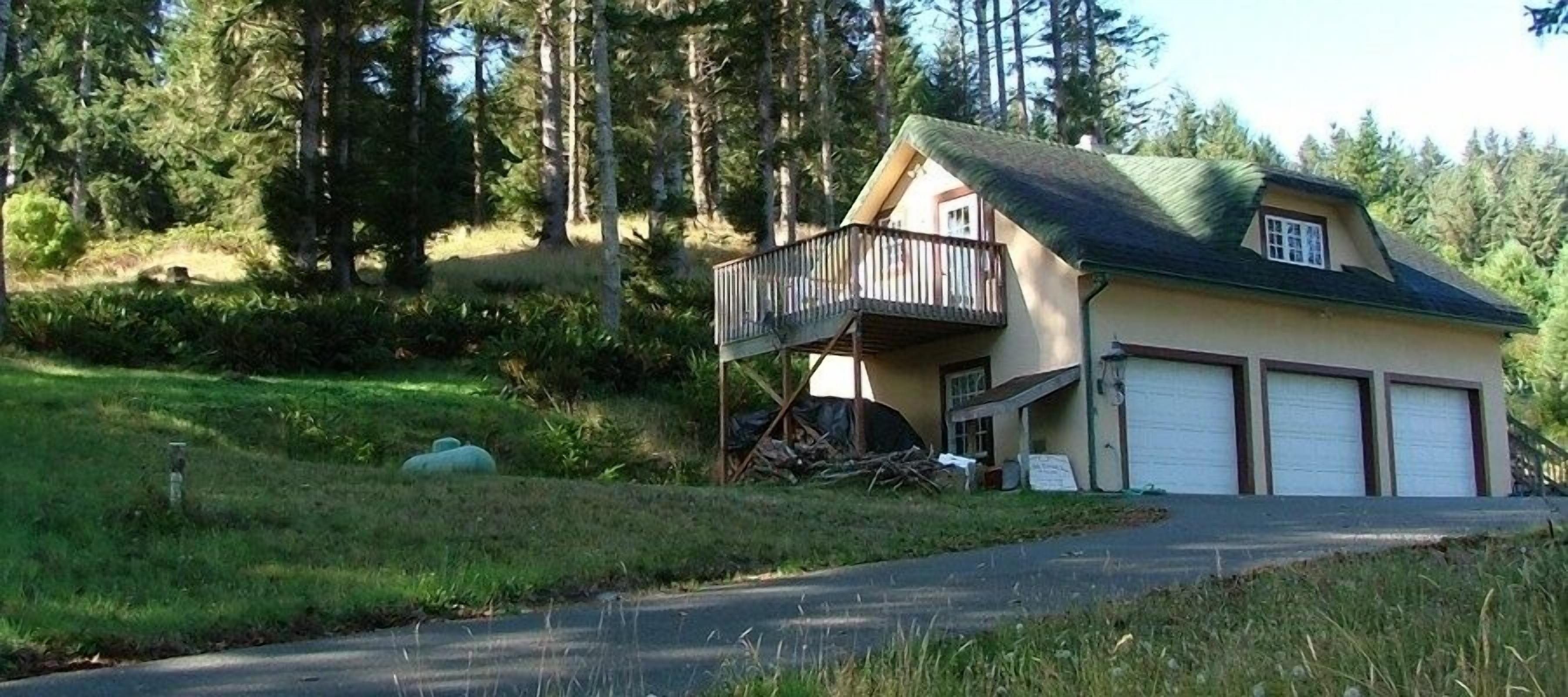 A two-story house with a balcony, a garage, and a driveway.