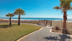 A paved pathway leading to a beach with palm trees and a wooden fence. - Summer House on Romar Beach by Wyndham Vacation Rentals (Orange Beach)