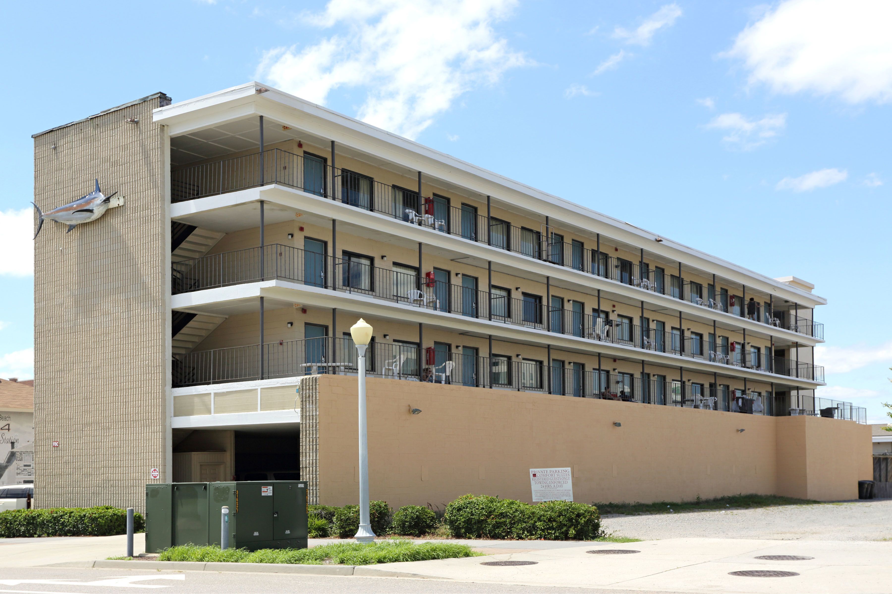 A multi-story hotel with balconies, a parking garage, and a street lamp.