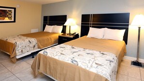 Hotellihuone, jossa on kaksi sänkyä, ja jokaisessa sängyssä on pääty, yöpöytä, lamppu ja seinälle kiinnitetty taideteos.