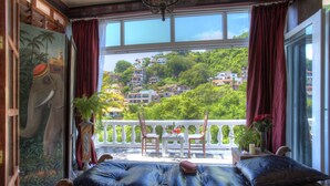 A room with a large window, a balcony, and a view of a hillside. - Rivera del Rio Boutique Hotel (Puerto Vallarta)