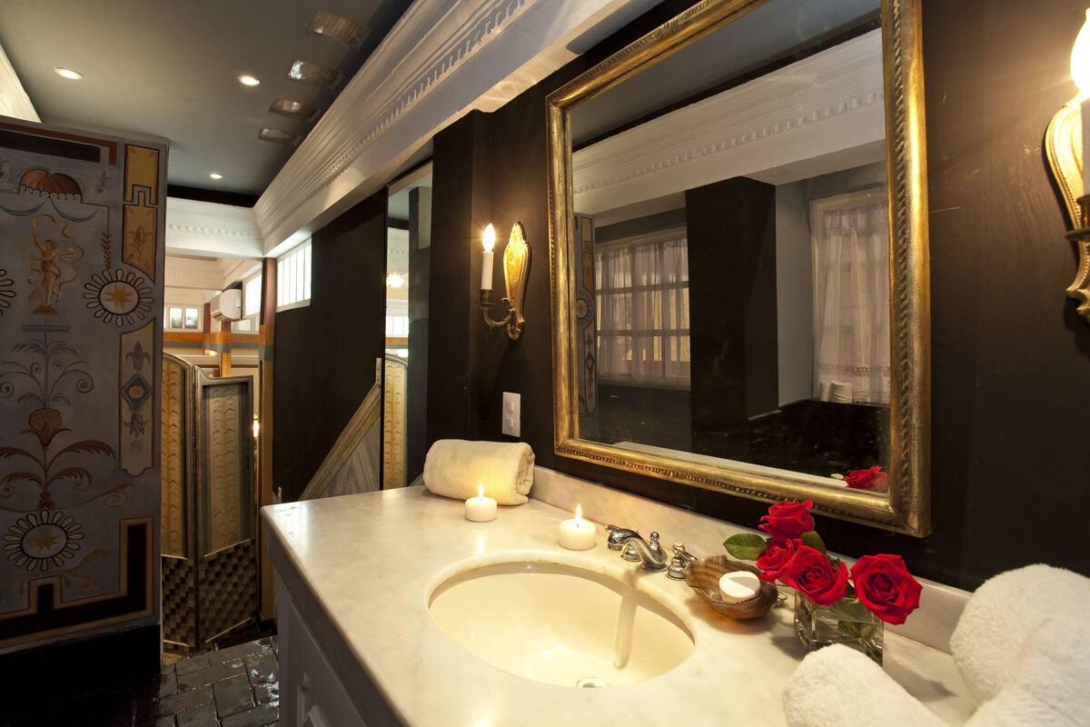 A bathroom with a large mirror, a sink, and two lit candles.