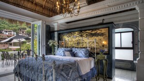 A bedroom with a large bed, a chandelier, and a view of the outside. - Rivera del Rio Boutique Hotel (Puerto Vallarta)