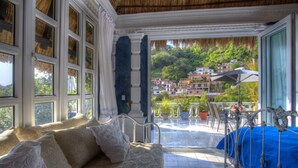 A room with a bed, a balcony with a view of a hillside, and a dining area with outdoor furniture. - Rivera del Rio Boutique Hotel (Puerto Vallarta)