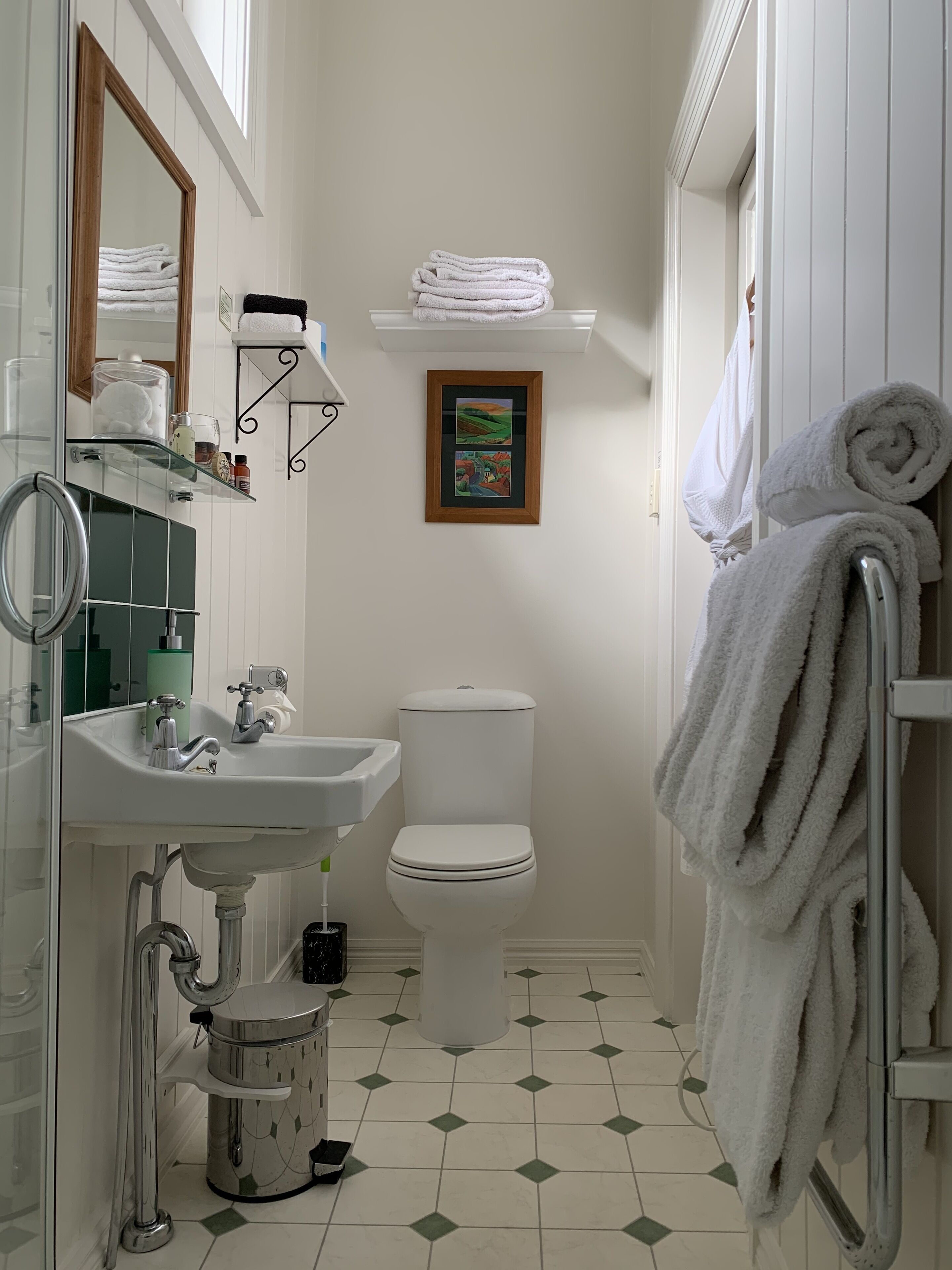 Un baño pequeño con lavamanos, inodoro y barra para toallas, todo en blanco.