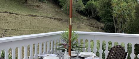 An outdoor patio with a table set for four, surrounded by wooden chairs, under a large white umbrella.