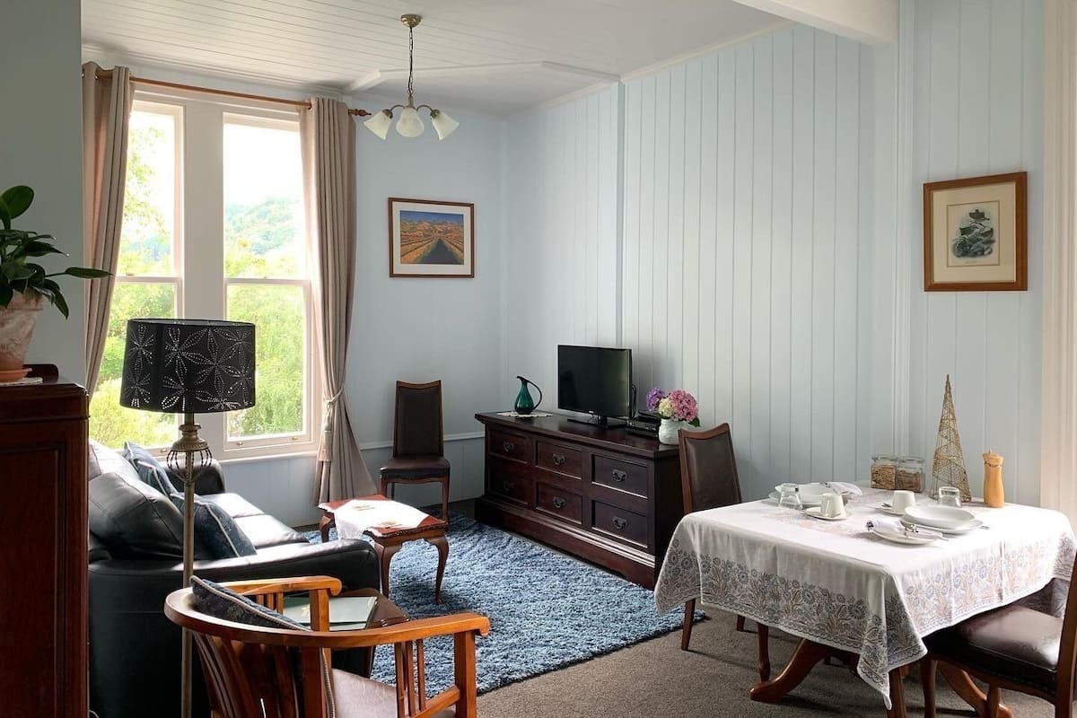 A room with a dining table set for four, a television, a cabinet, a sofa, and a chair.