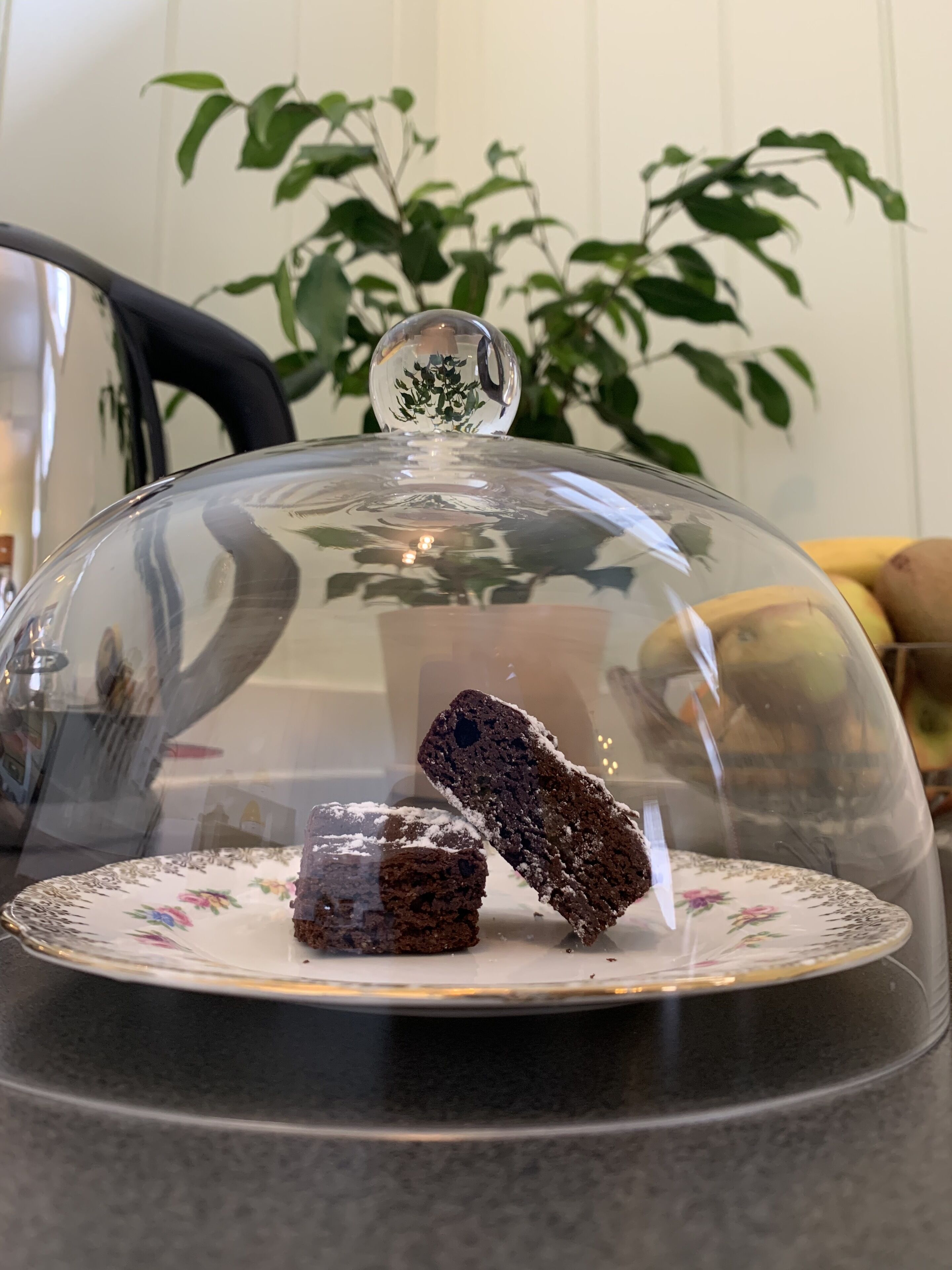 En glasdækket dessertudstilling med en tallerken med blomster under.