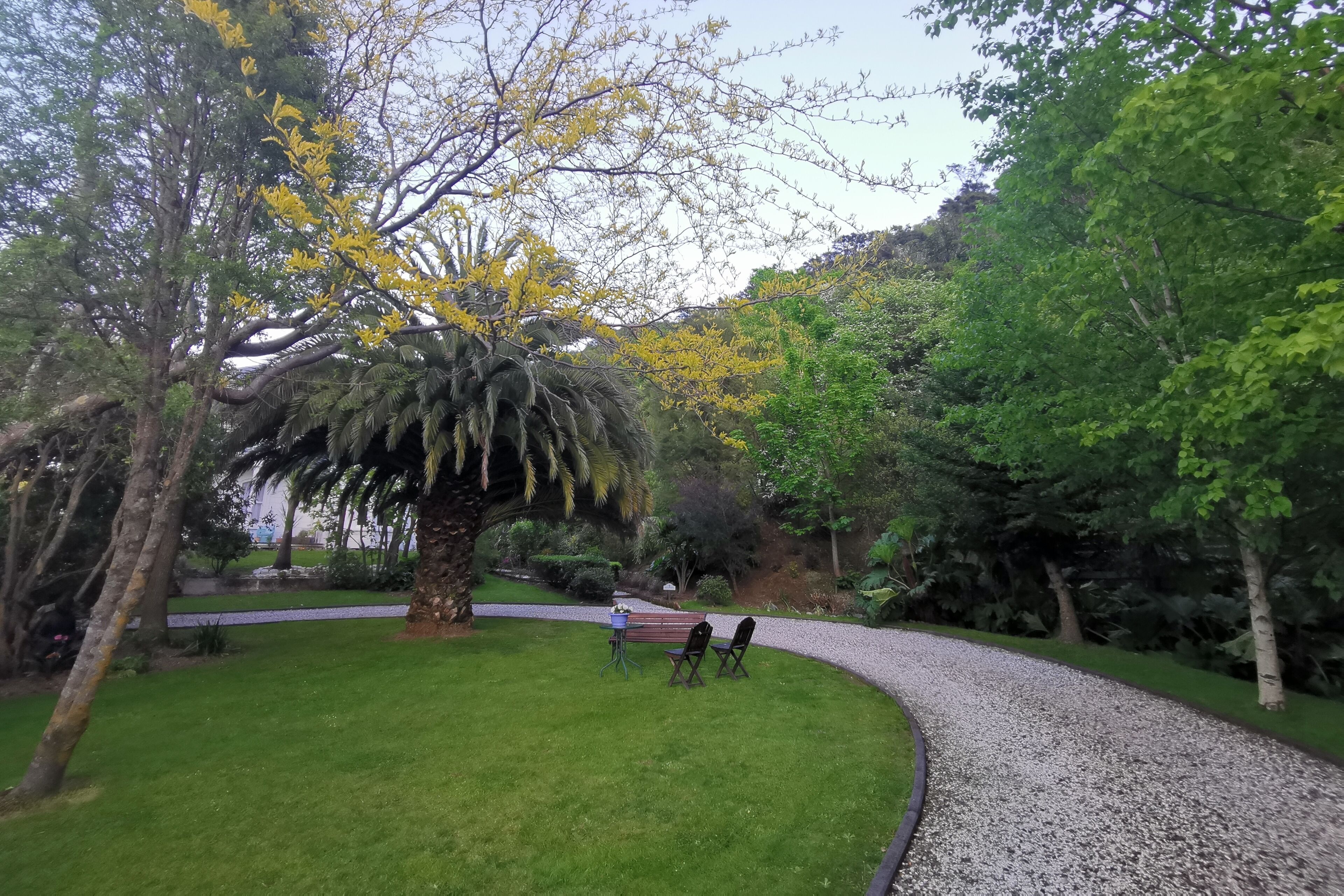 Ein Garten mit einem gewundenen Kiesweg, einer Bank und einem Tisch mit Stühlen.
