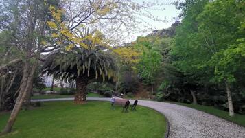 Un jardín con un sendero de grava curvo, un banco y una mesa con sillas.