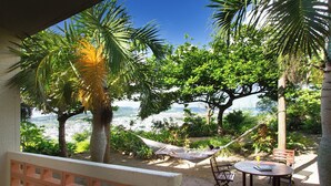 A hammock, a table, and chairs in a shaded outdoor area with a view of a cityscape. - Coco Garden Resort Okinawa (Uruma)