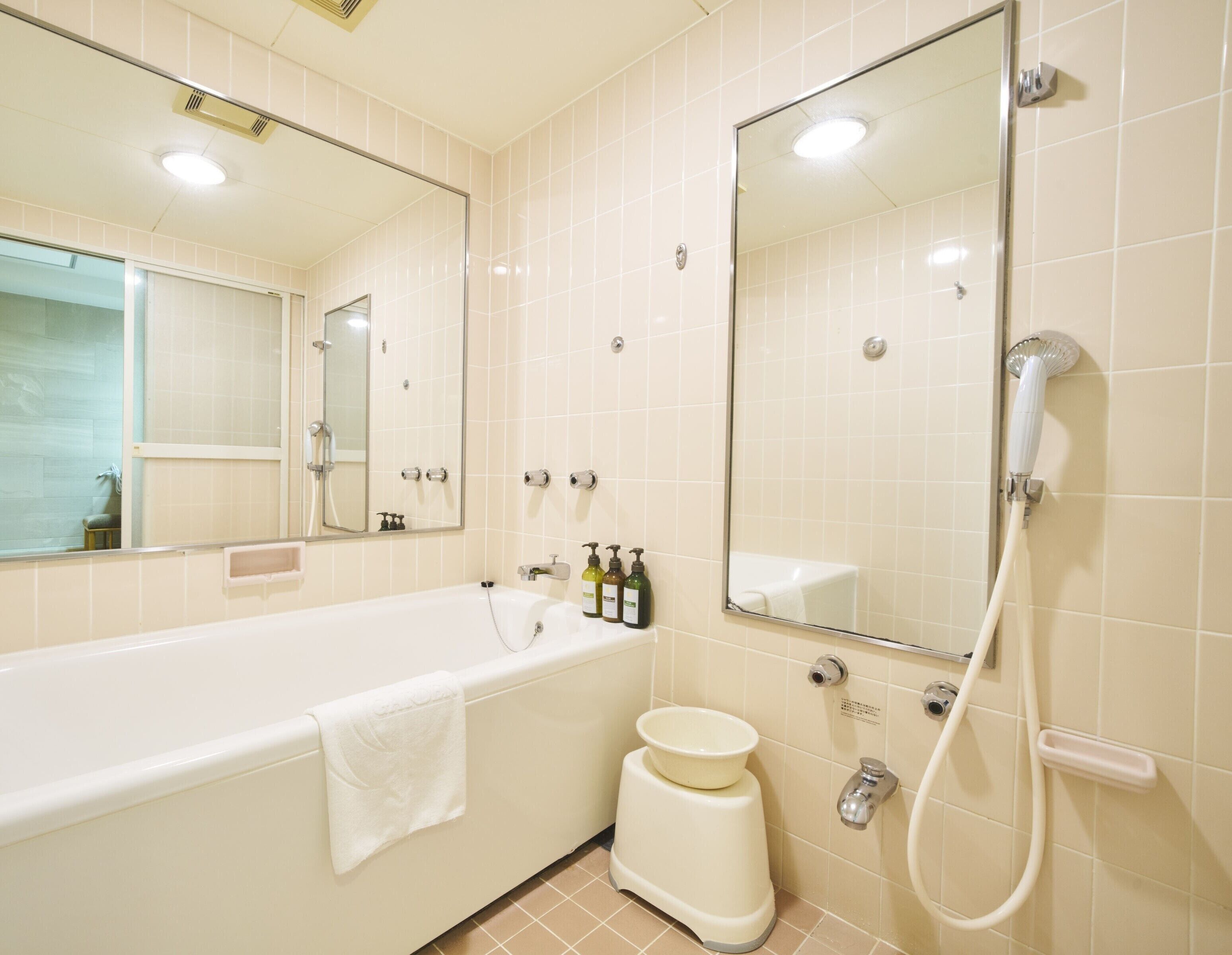 Un baño moderno con bañera, inodoro, bidé y un espejo grande.