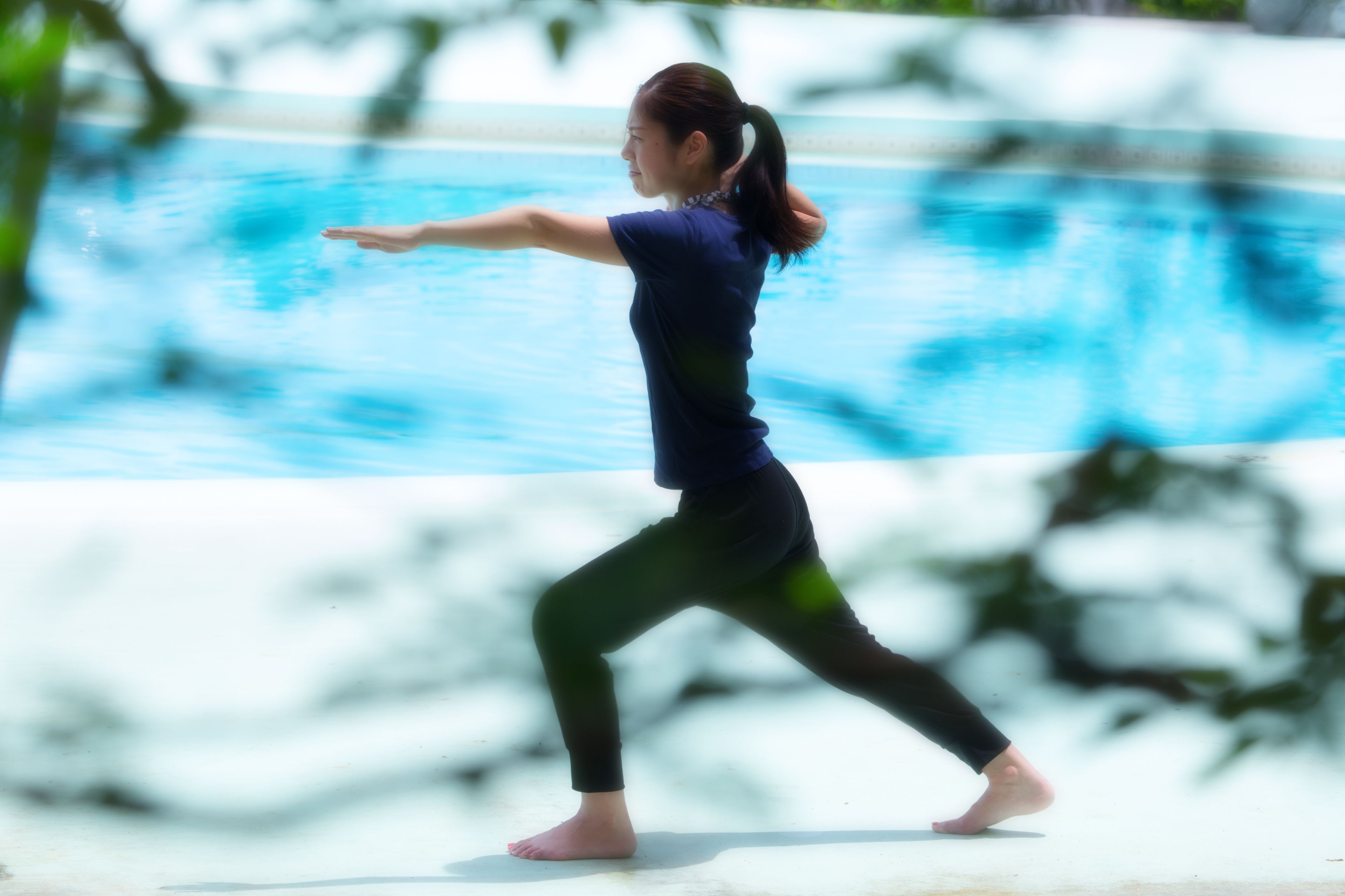 Eine Person führt eine Yoga-Pose am Pool aus.
