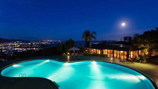 A swimming pool with a view of a cityscape at night. - Coco Garden Resort Okinawa (Uruma)