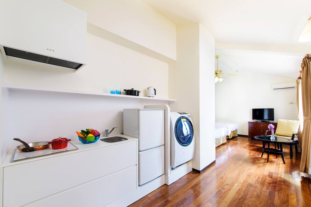 A compact kitchen with a sink, a washing machine, and a small dining area with a table and chair.