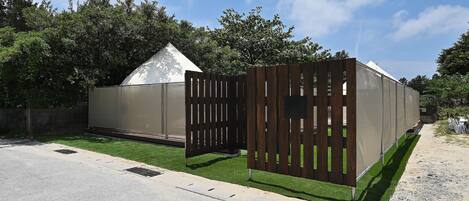 Un bâtiment doté d’un grand espace clos, d’une clôture en bois et d’une pelouse à l’avant.