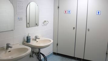 A bathroom with two sinks, a mirror, and a toilet stall.