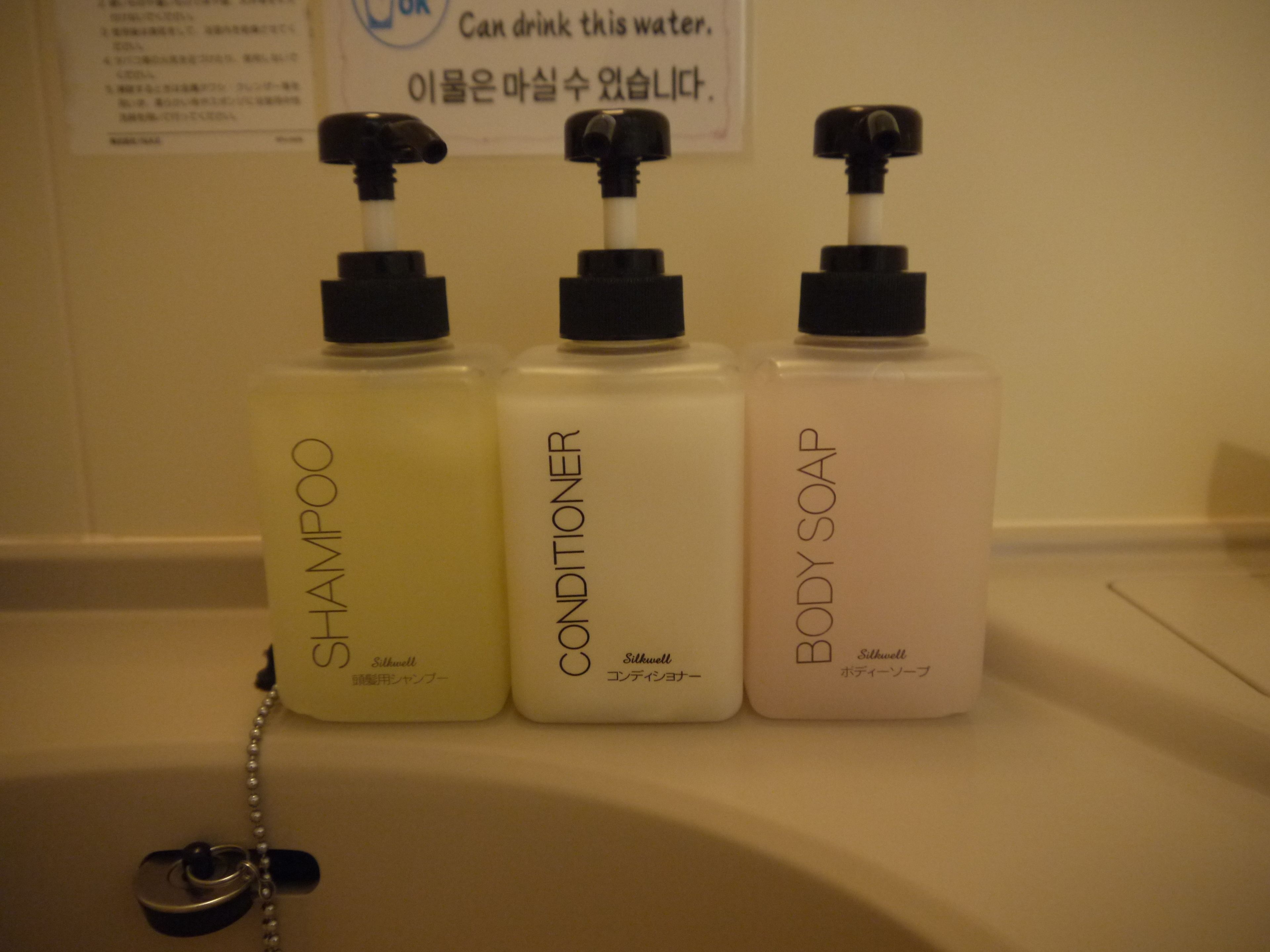 Three bottles of Silkwell products: shampoo, conditioner, and body soap, arranged on a bathroom counter.