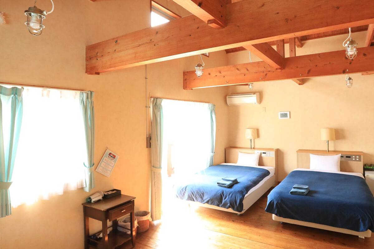 Una habitación con dos camas, vigas de madera, un escritorio y una mesita.