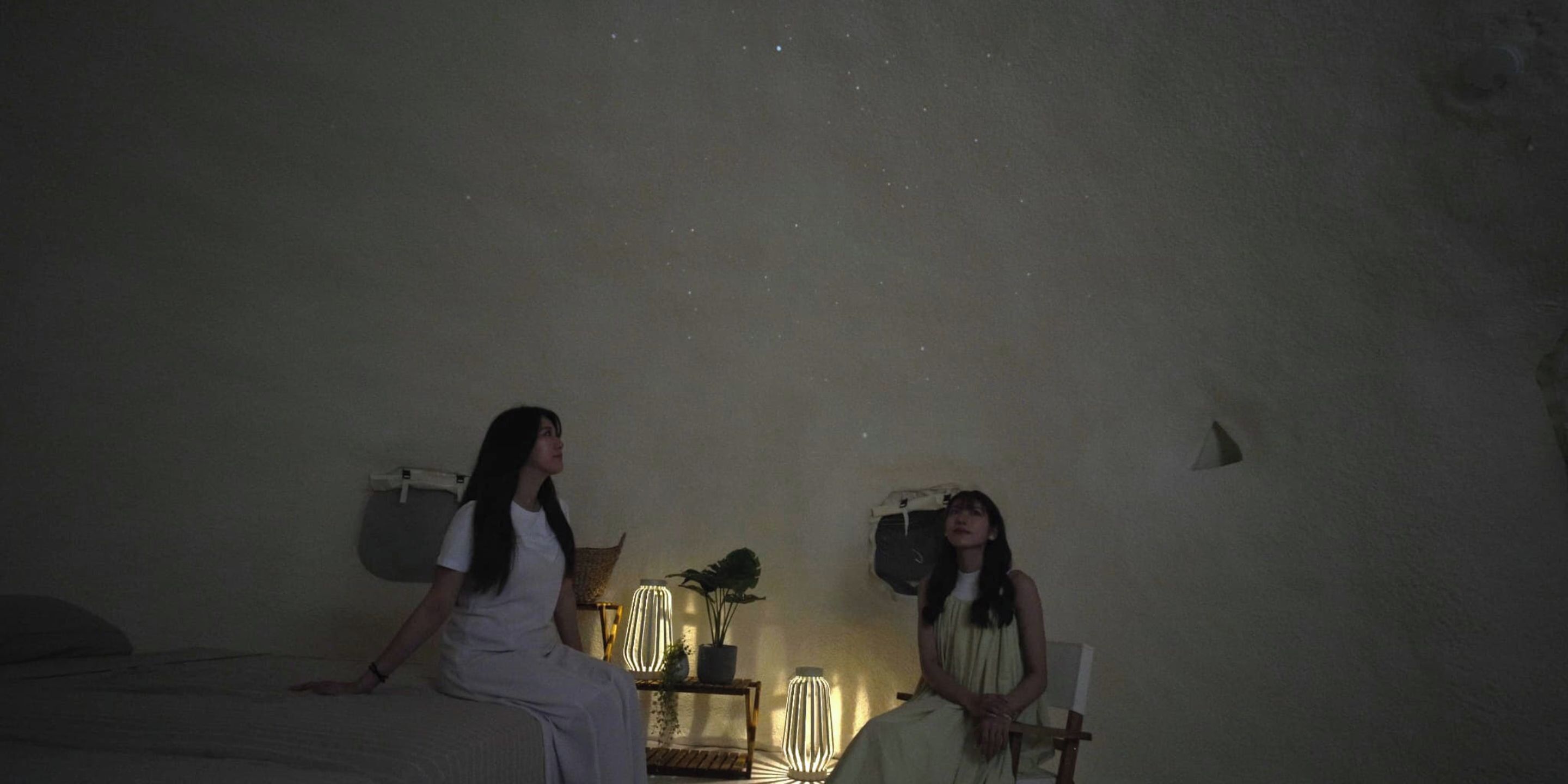 Um quarto com uma cama, uma cadeira, um abajur e uma prateleira na parede.