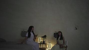 Um quarto com uma cama, uma cadeira, um abajur e uma prateleira na parede.