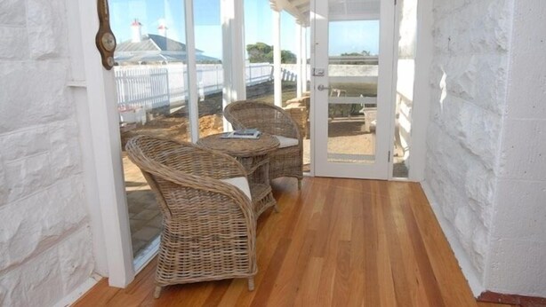 Une terrasse couverte, aménagée avec des meubles en osier, offrant une vue sur la mer.