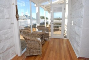A covered patio with wicker furniture and a view of the sea.