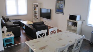 Un salon avec un canapé, une table basse, un téléviseur et une bibliothèque.