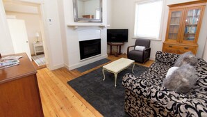 Un salon avec une cheminée, un téléviseur, un canapé et un meuble.