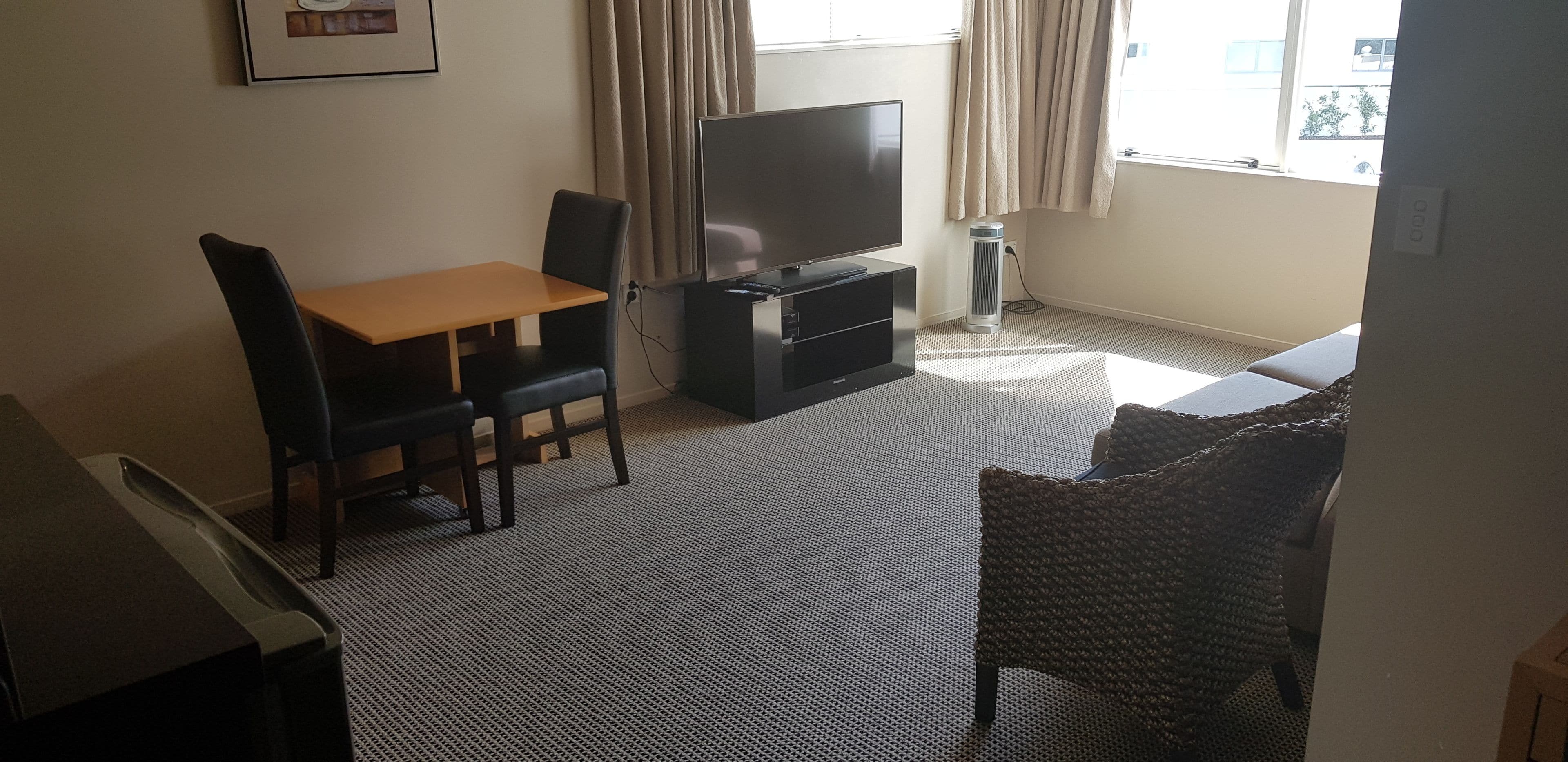 A small, furnished room with a TV, a table, and two chairs.