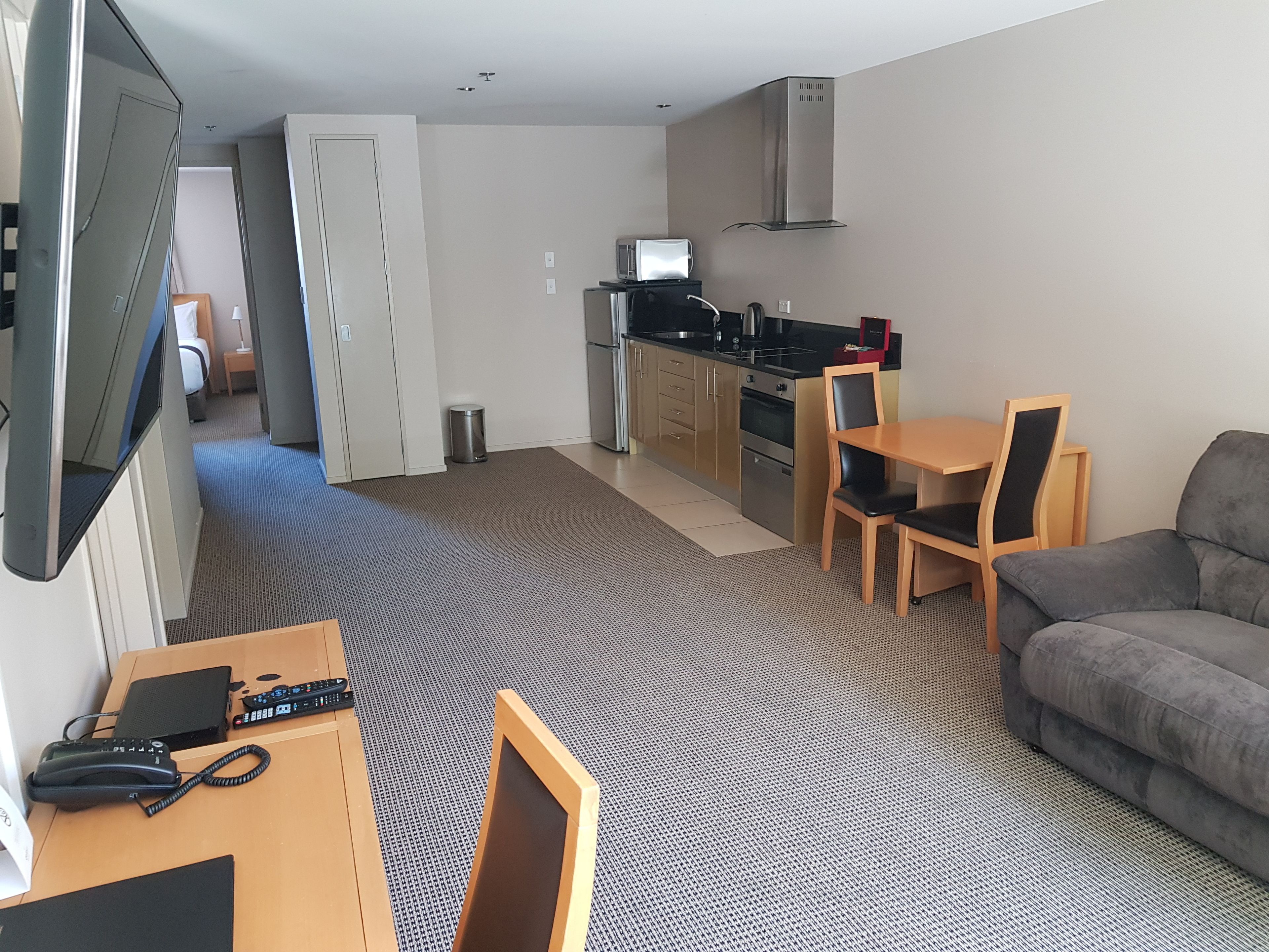 Une chambre d’hôtel compacte comprenant un coin cuisine, un espace repas, un canapé et un téléviseur.