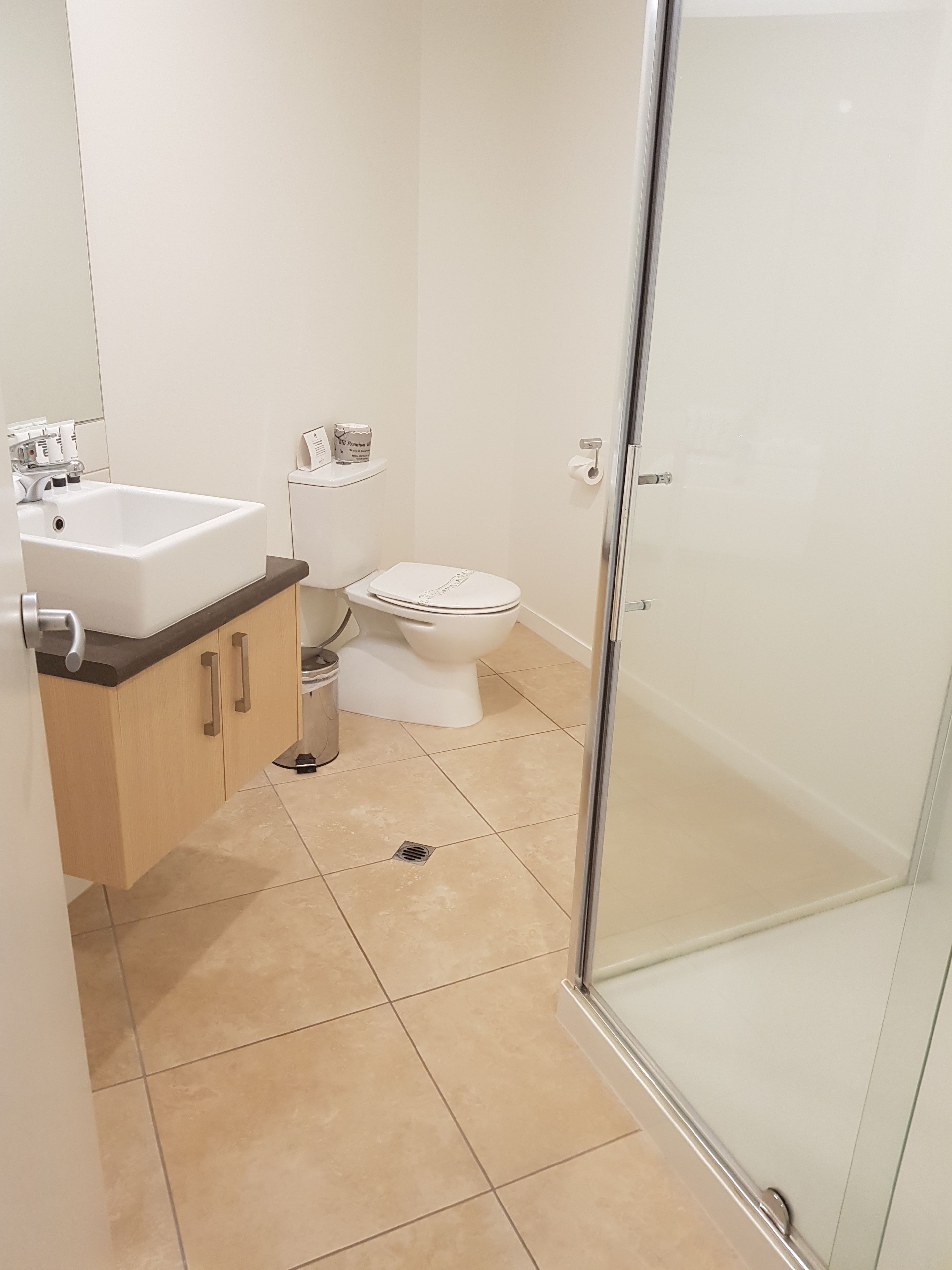 A modern bathroom with a white sink, toilet, and shower.