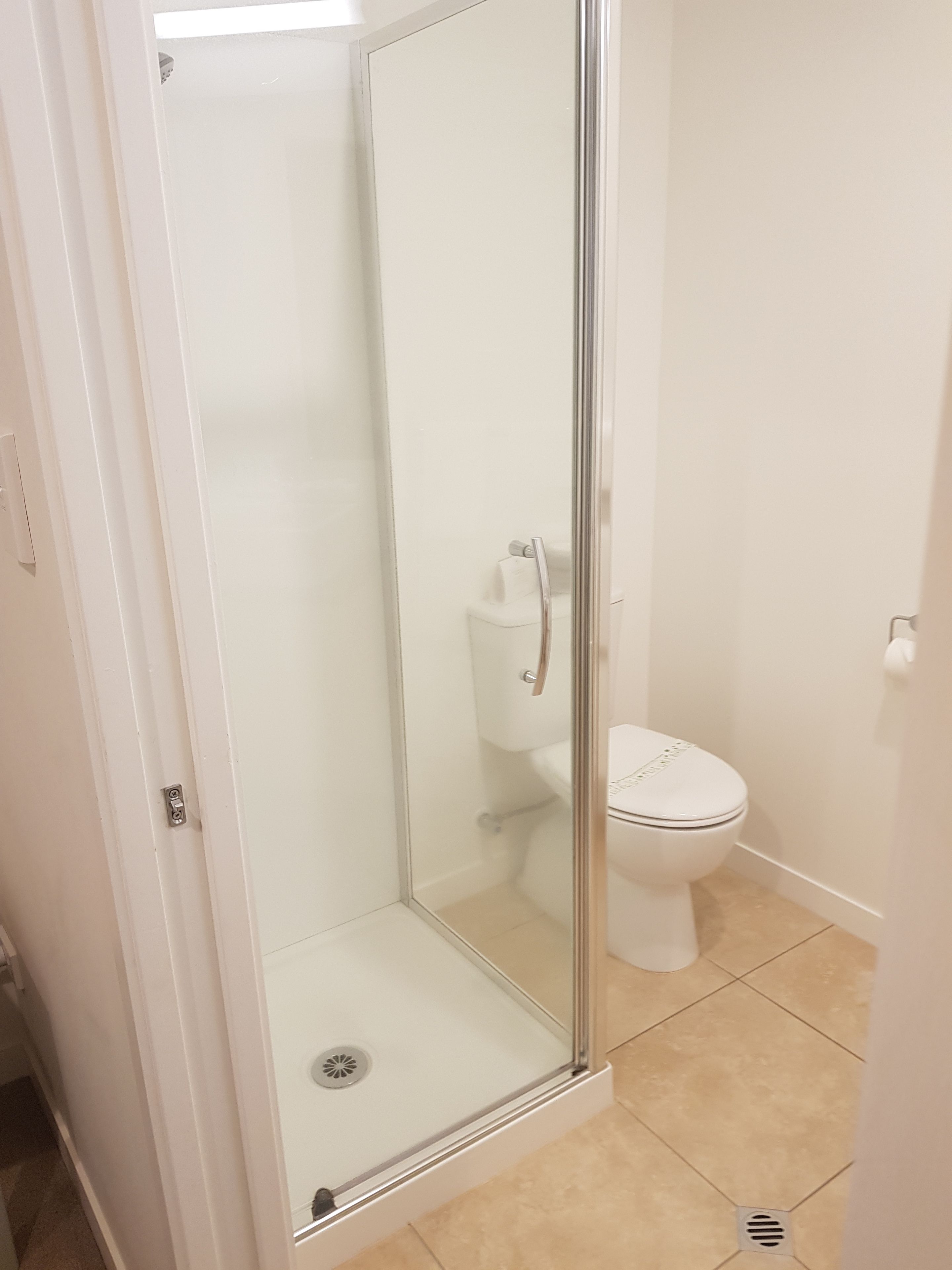 A bathroom with a glass-enclosed shower, a toilet, and a sink.