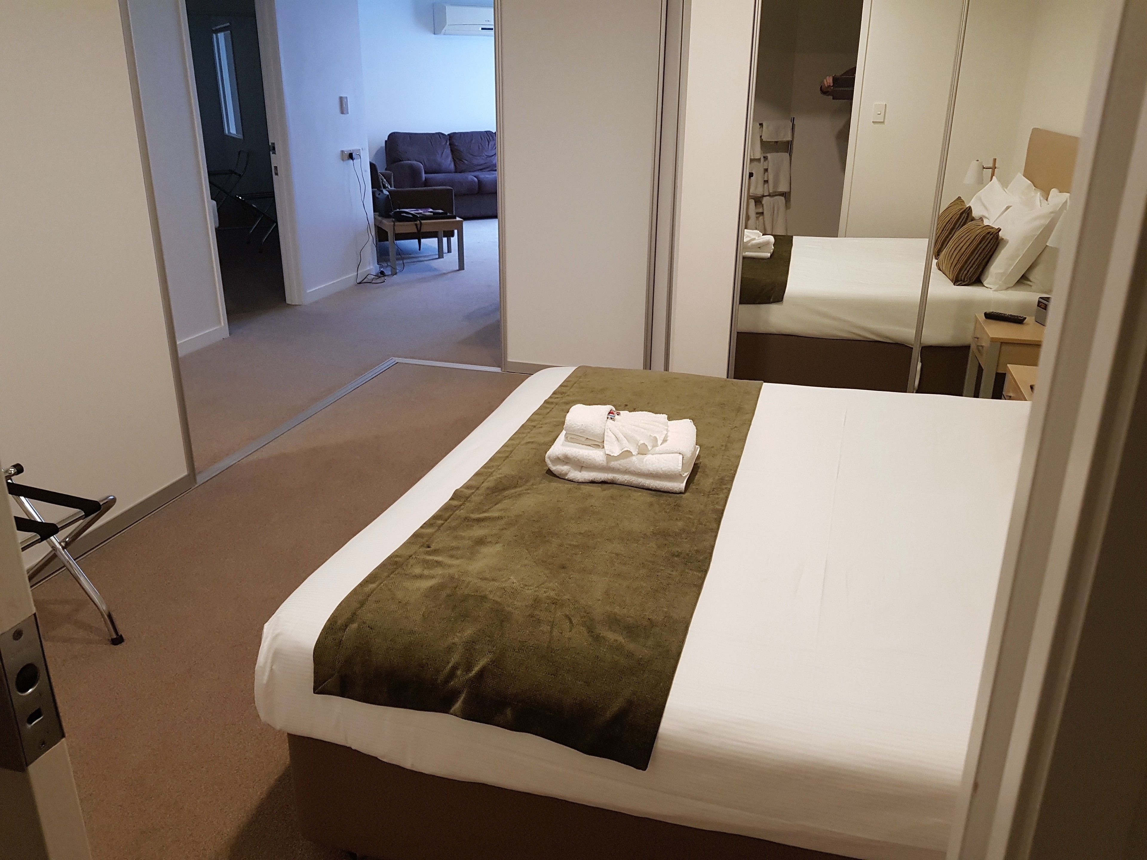 A hotel room with a bed, a small table, and a chair.