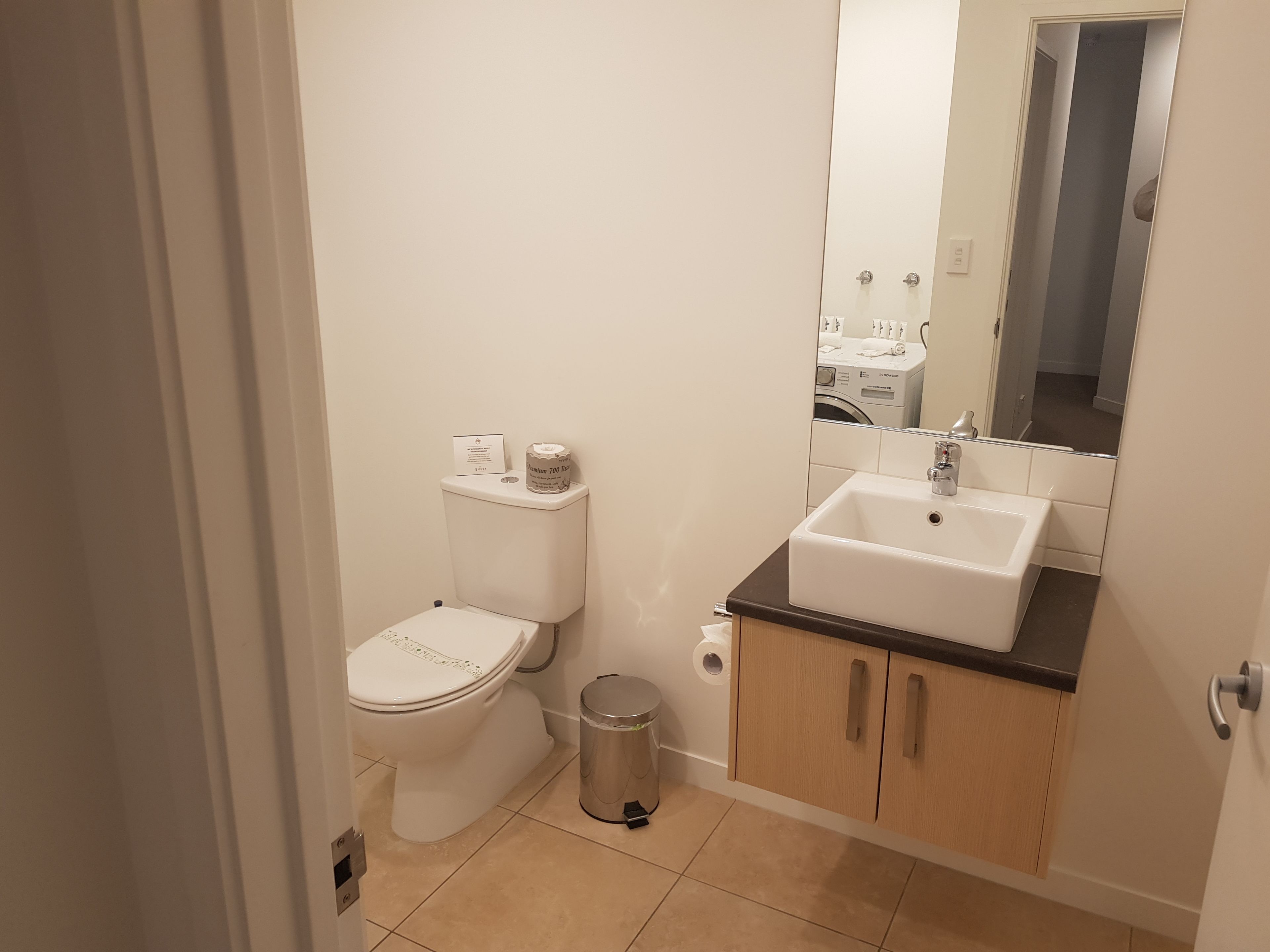 A small, clean bathroom with a toilet, sink, and mirror.