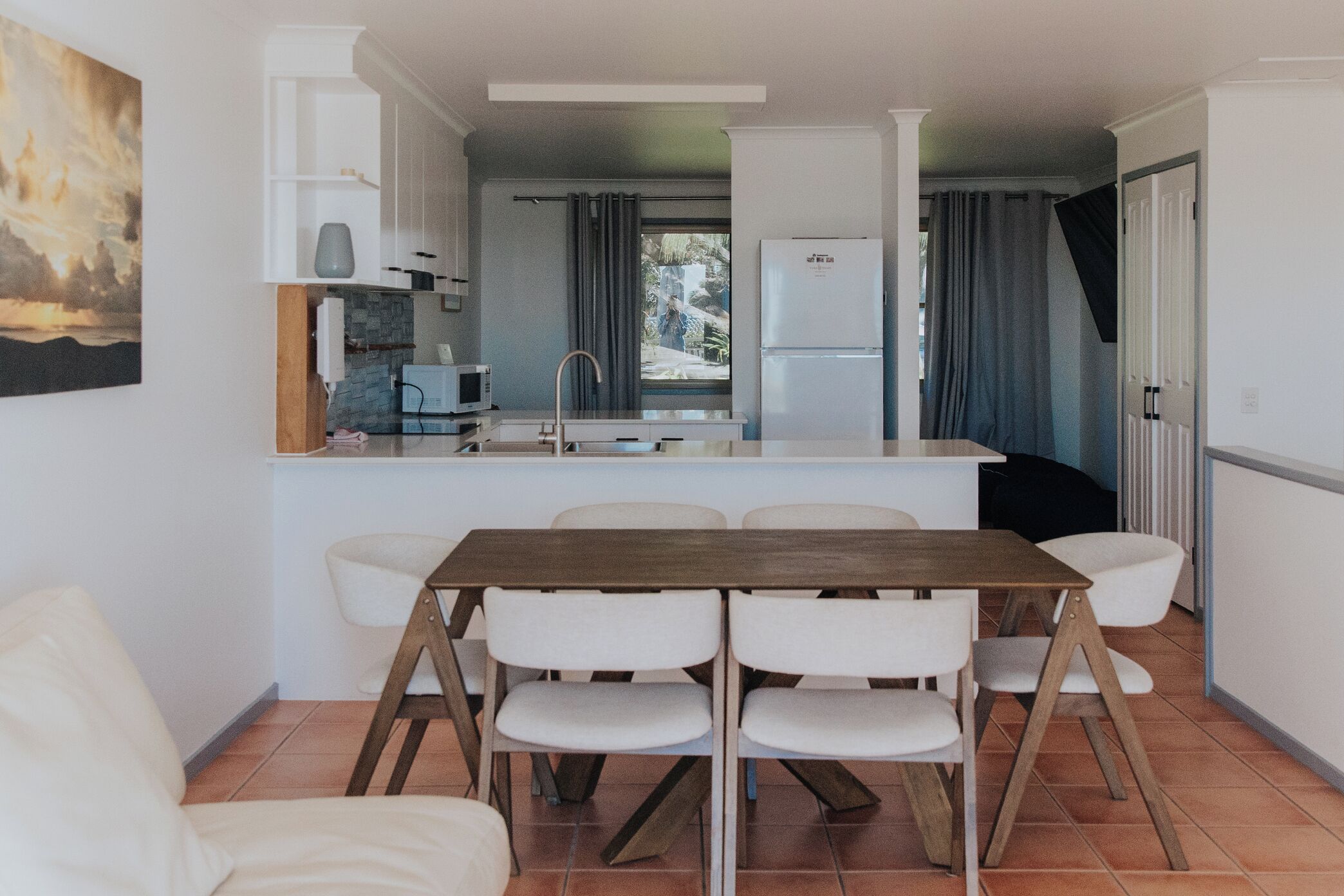 Una cucina compatta con zona pranzo, arredi bianchi e vista dalla finestra.