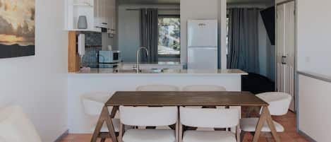 Una cucina compatta con zona pranzo, arredi bianchi e vista dalla finestra.