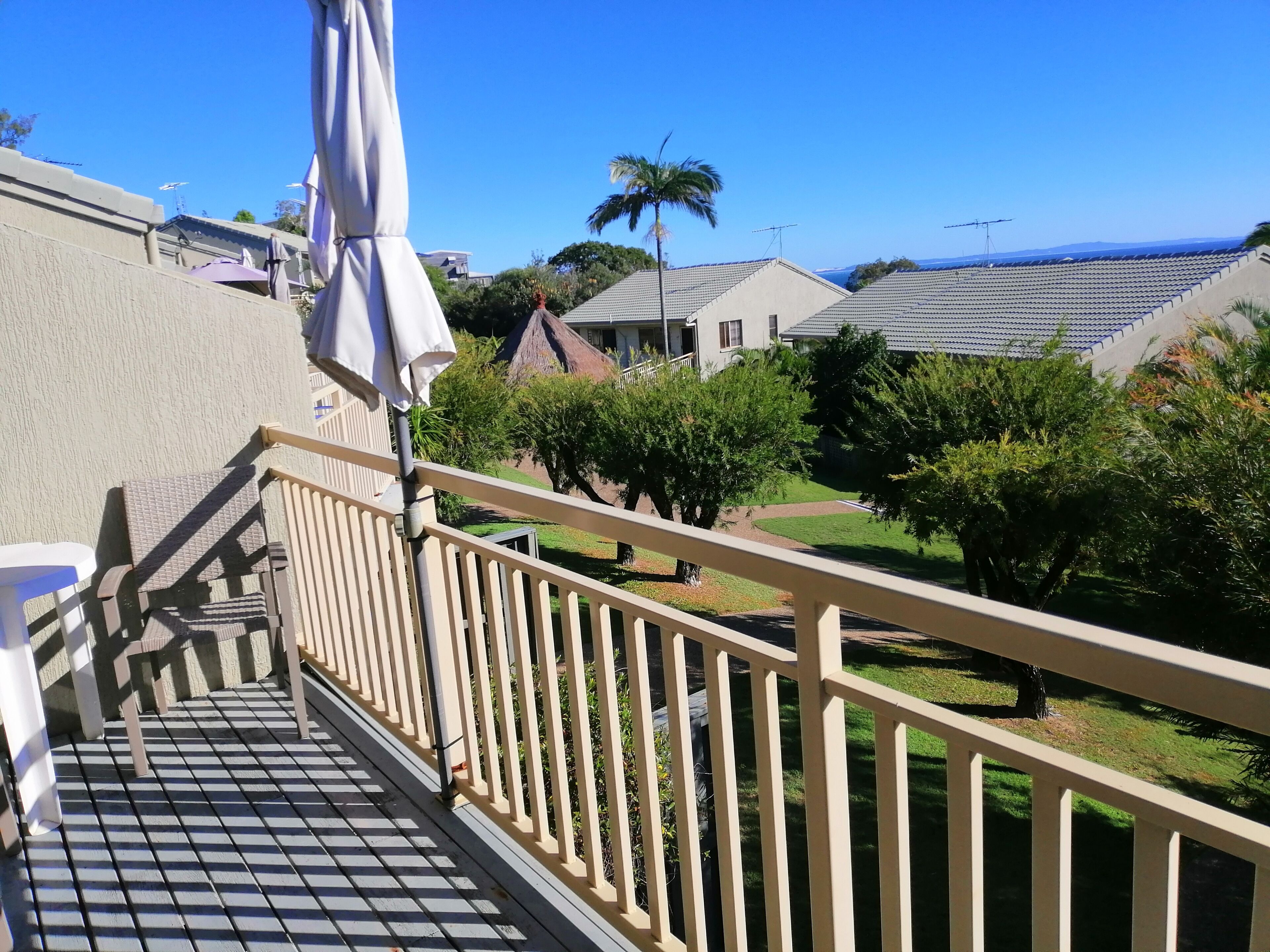 A balcony with a view of a residential area, including houses and a palm tree.