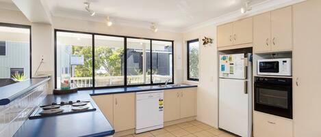 A modern kitchen with a blue countertop, white cabinets, a dishwasher, a refrigerator, and an oven.