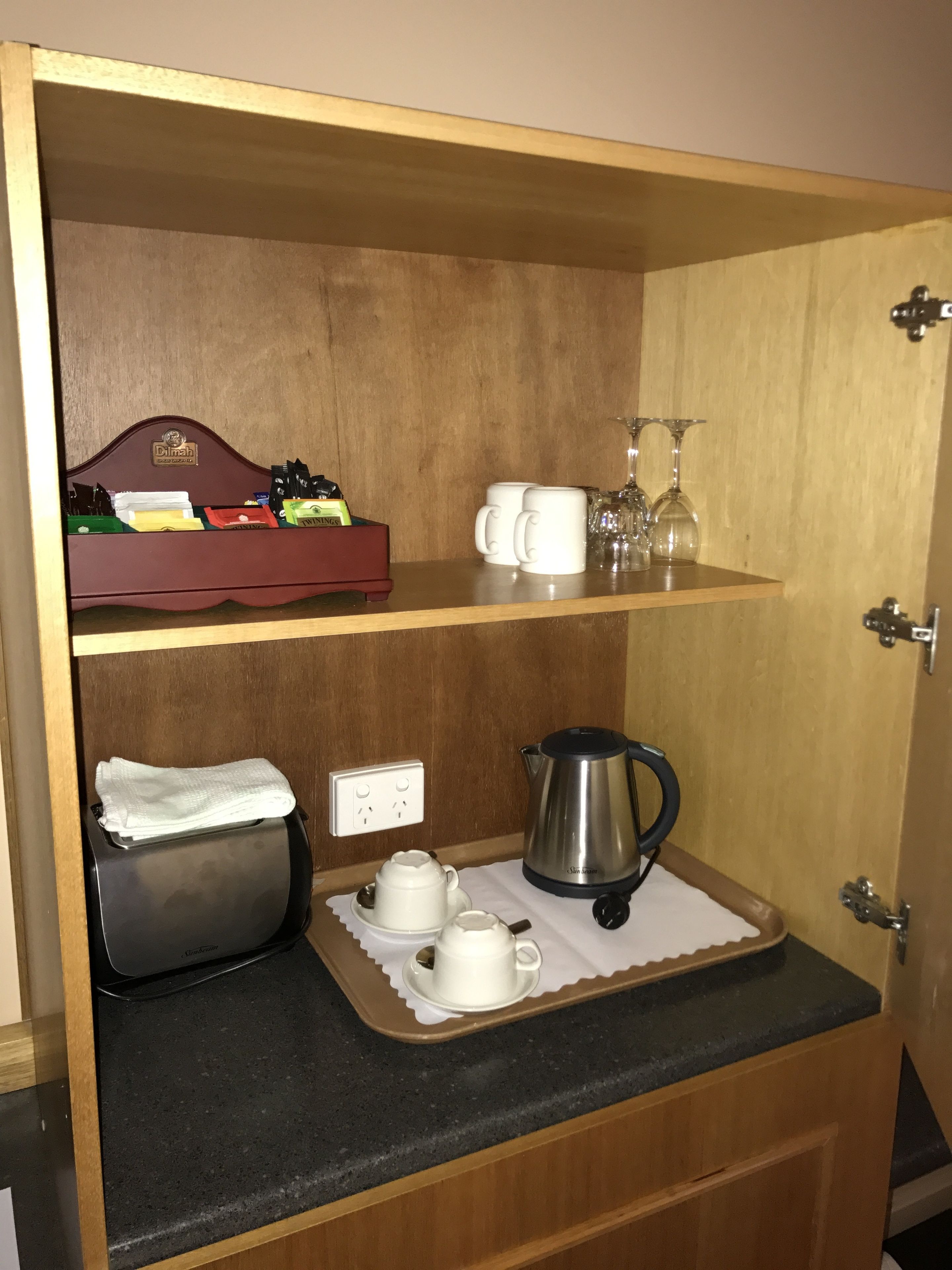 Una zona de cocina con cafetera, juego de té y hervidor sobre la encimera.