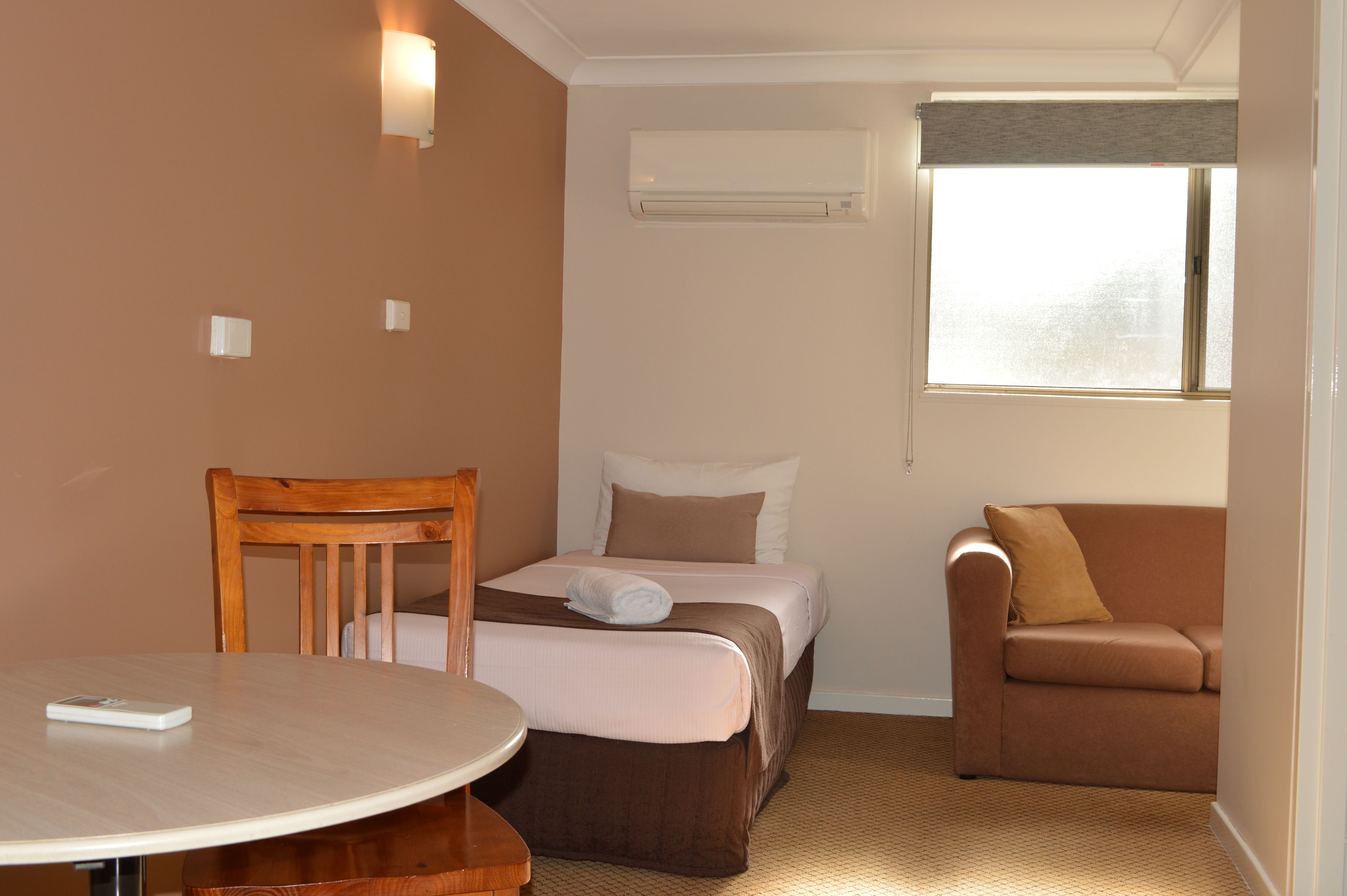 Una habitación de hotel con una cama, una silla, una mesa y un ventanal.