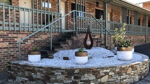 Un edificio con fachada de ladrillo, base de piedra y escalera de metal. Hay plantas en macetas y un adorno colgante.