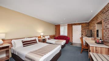 Quarto de hotel com duas camas, uma escrivaninha, uma cadeira vermelha e uma televisão.