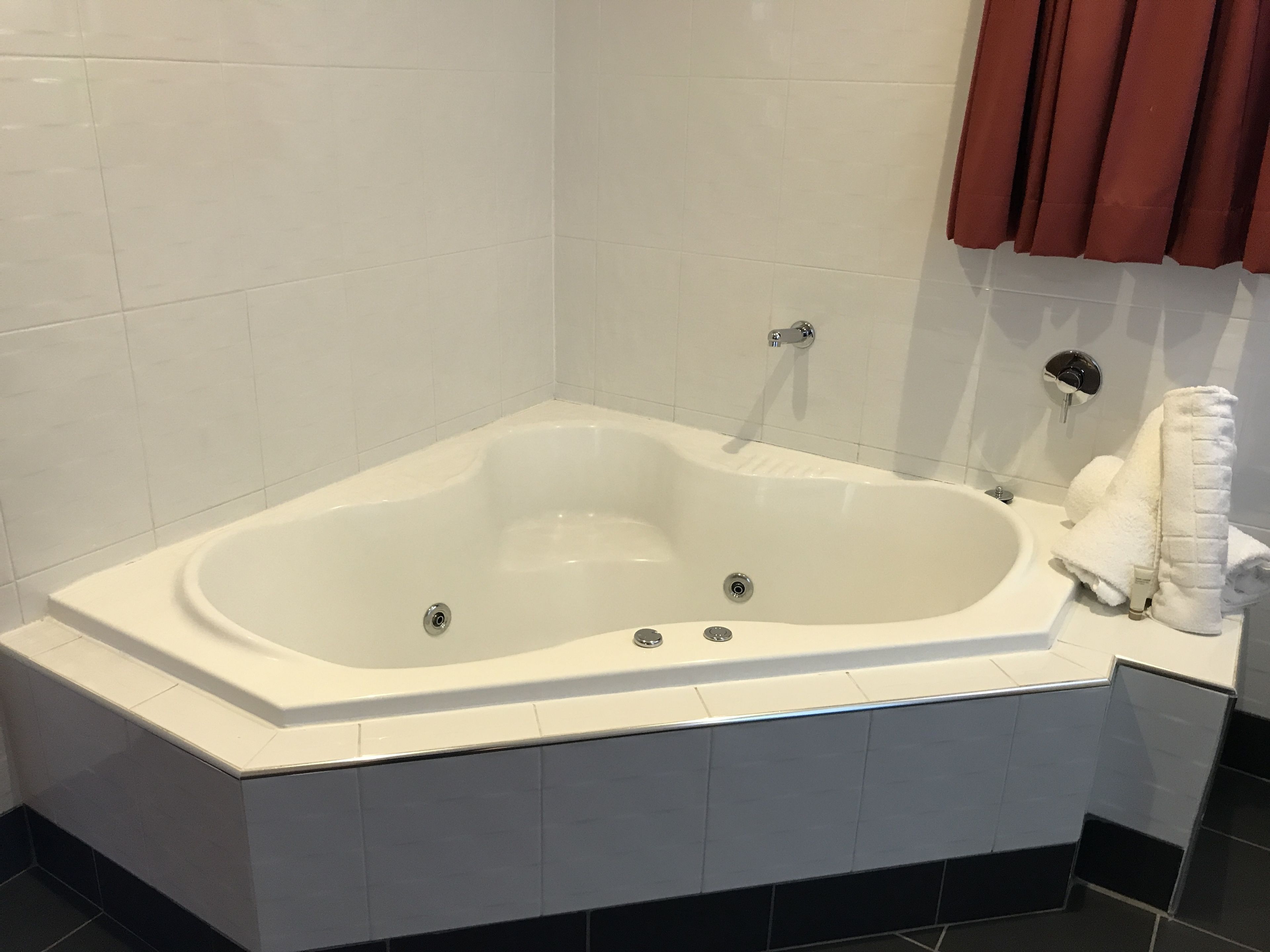 A modern bathroom with a freestanding bathtub, white tiles, and a towel rack.
