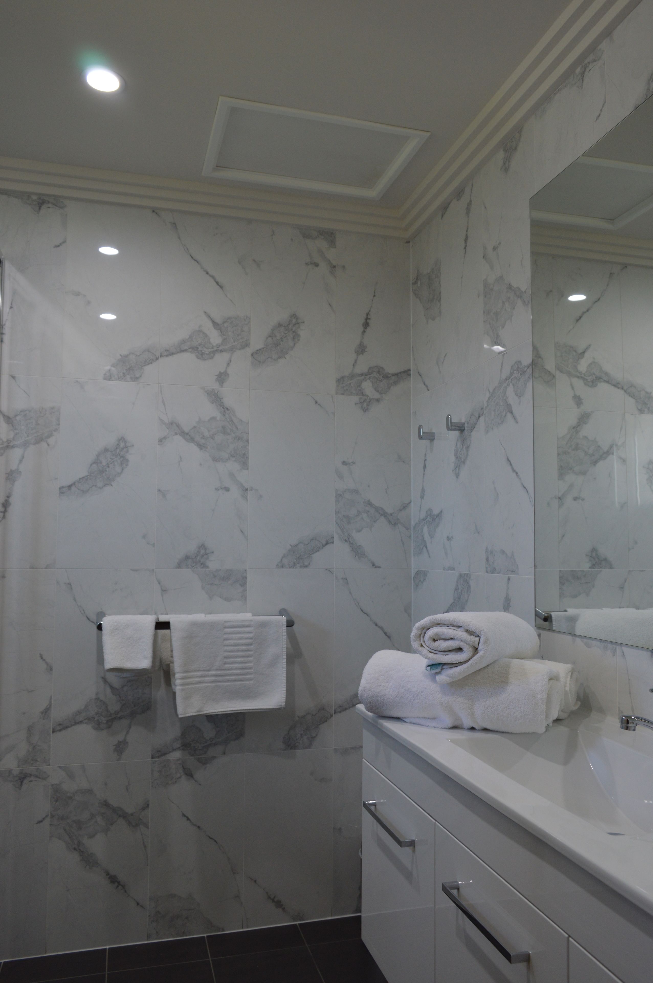 A bathroom with marble walls, a white sink, and a mirror.